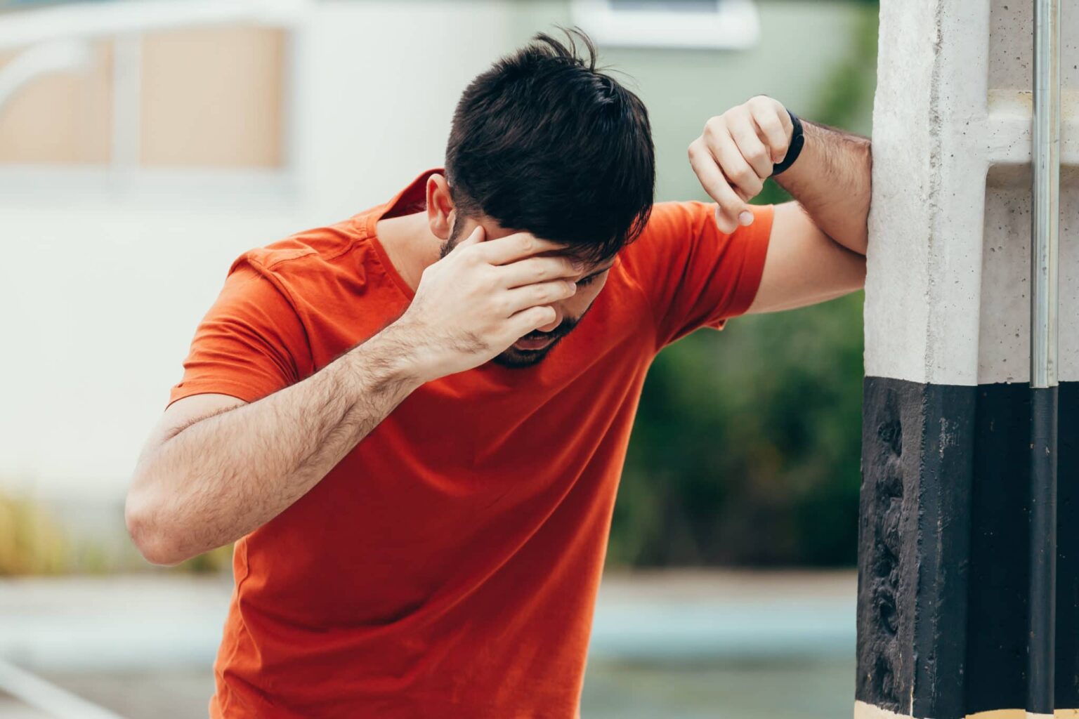 Man leaning against a pole because he is dizzy