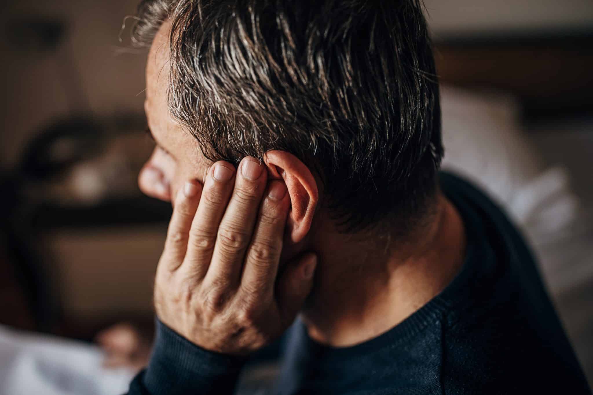a man touches his ear