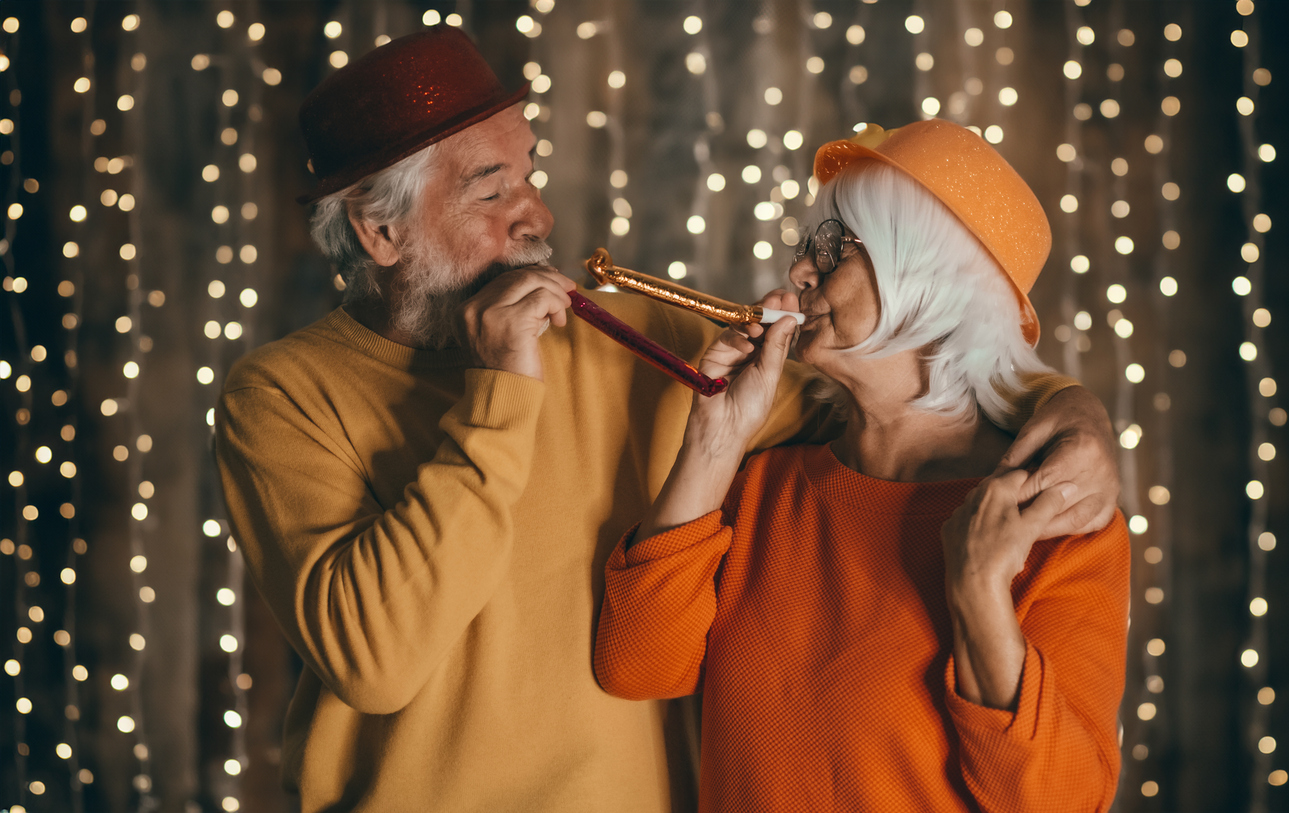 Happy couple at a New Years Eve party blowing into noisemakers